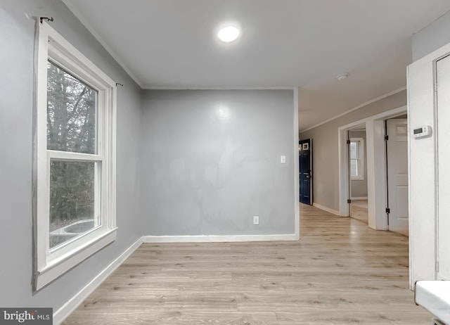 empty room with crown molding and light wood-type flooring