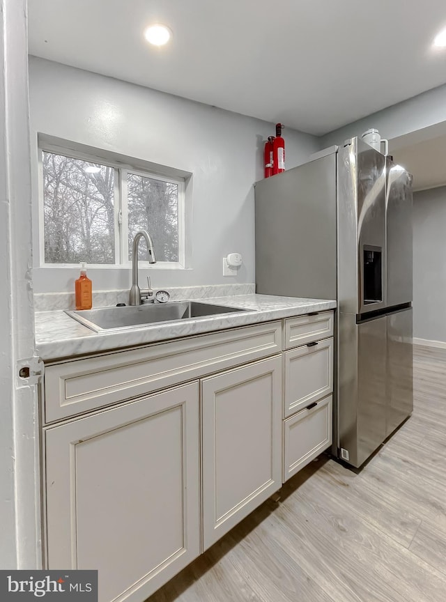 kitchen featuring stainless steel fridge with ice dispenser, light wood-type flooring, and sink