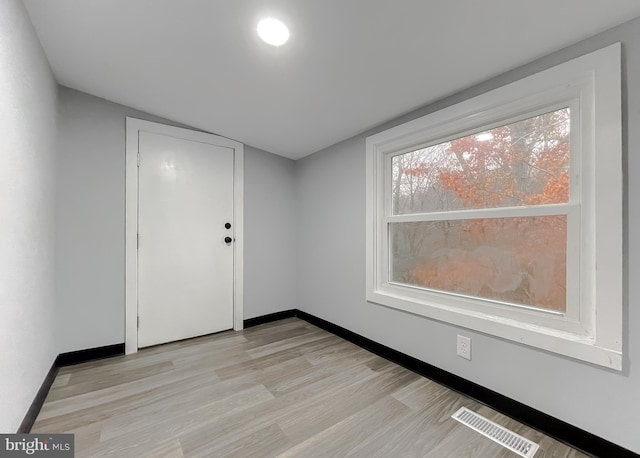 spare room featuring lofted ceiling and light wood-type flooring