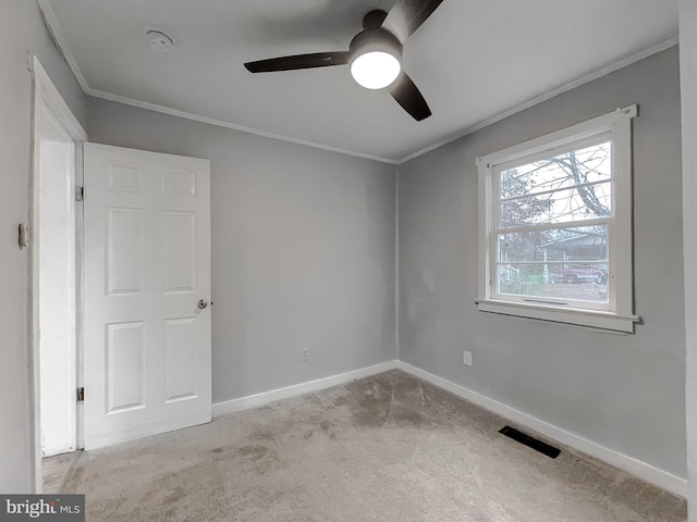 carpeted empty room with ceiling fan and crown molding