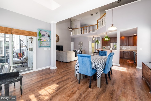 dining room featuring a towering ceiling, dark hardwood / wood-style floors, and ceiling fan