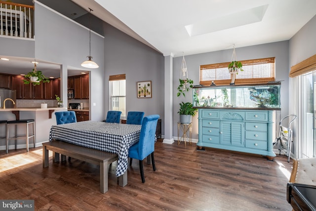 dining area featuring dark hardwood / wood-style floors, high vaulted ceiling, and a skylight