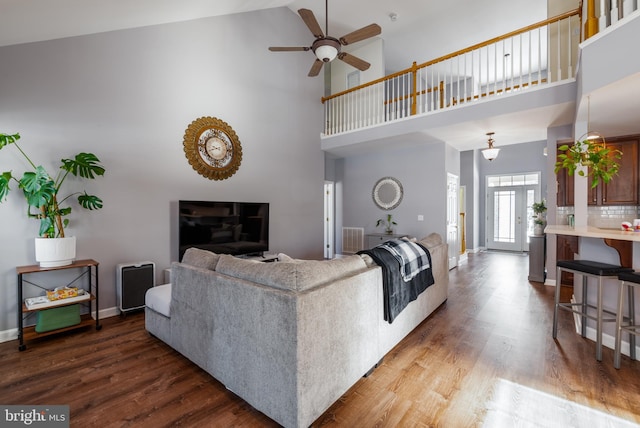 living room featuring ceiling fan, a towering ceiling, and hardwood / wood-style flooring