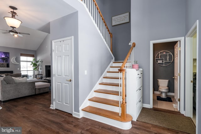 stairs with hardwood / wood-style floors, high vaulted ceiling, and ceiling fan