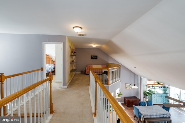 corridor with light carpet and vaulted ceiling