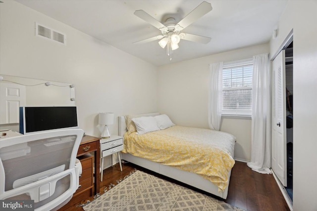 bedroom with ceiling fan, dark wood-type flooring, and a closet