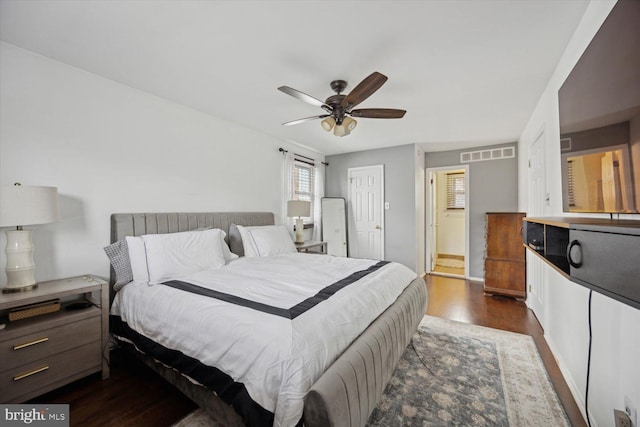 bedroom with dark hardwood / wood-style floors, ensuite bath, and ceiling fan