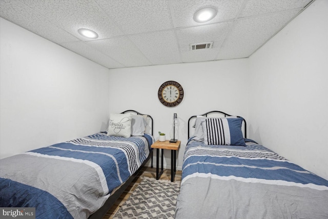 bedroom with dark hardwood / wood-style floors and a drop ceiling