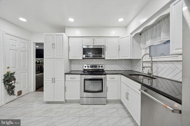 kitchen with tasteful backsplash, sink, white cabinets, and stainless steel appliances