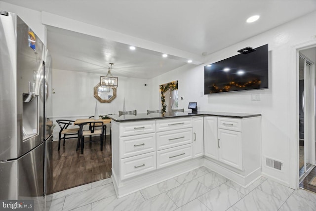 kitchen with kitchen peninsula, stainless steel fridge, light wood-type flooring, decorative light fixtures, and white cabinets