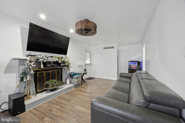 living room featuring wood-type flooring and a brick fireplace