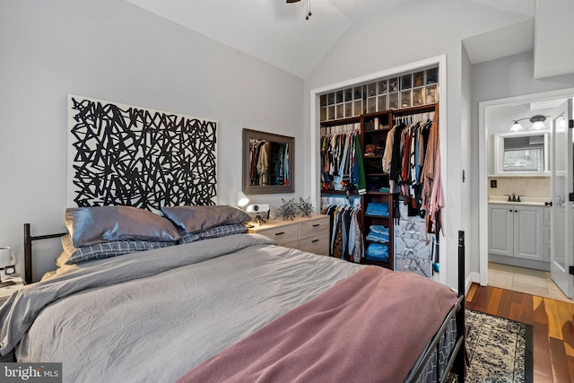 bedroom with ensuite bath, vaulted ceiling, sink, light hardwood / wood-style flooring, and a closet