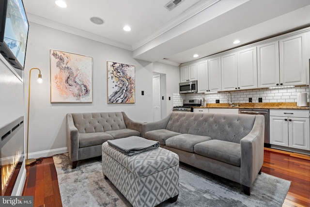 living room with crown molding, sink, and hardwood / wood-style flooring