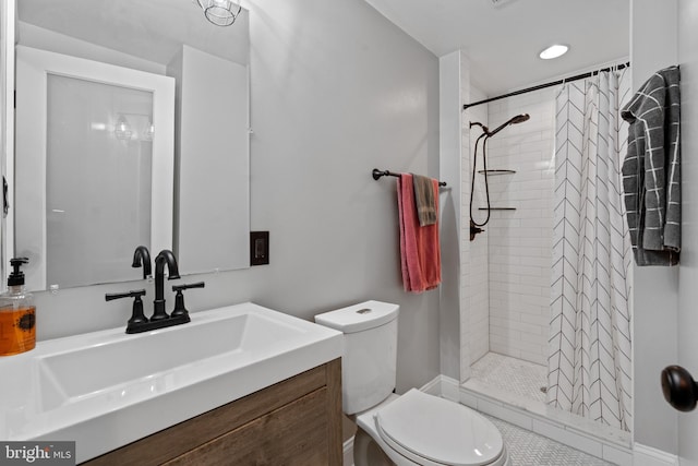 bathroom with a tile shower, vanity, and toilet