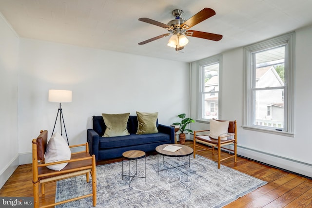 living room featuring hardwood / wood-style flooring, baseboard heating, and ceiling fan