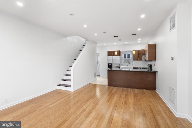 kitchen with crown molding, hanging light fixtures, light hardwood / wood-style flooring, decorative backsplash, and appliances with stainless steel finishes