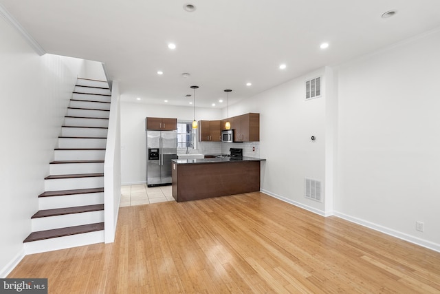 kitchen with pendant lighting, backsplash, crown molding, light wood-type flooring, and stainless steel appliances