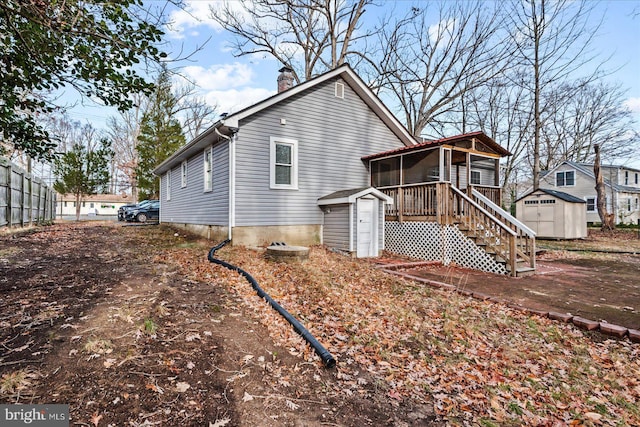 back of property with a sunroom and a shed