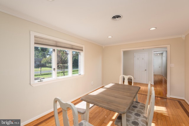 dining space featuring ornamental molding, light wood-type flooring, visible vents, and baseboards