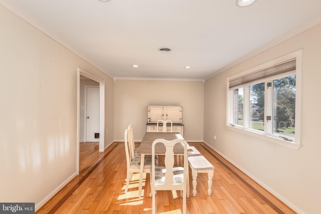 dining space featuring light wood-style floors, visible vents, ornamental molding, and baseboards