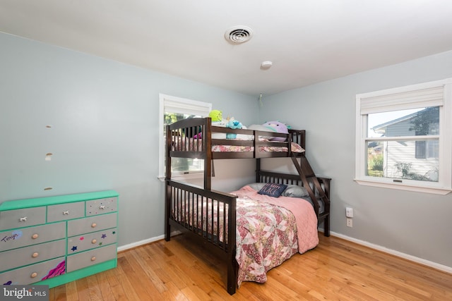 bedroom with hardwood / wood-style floors, visible vents, and baseboards