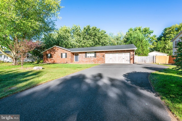 ranch-style house featuring aphalt driveway, an attached garage, brick siding, fence, and a front yard