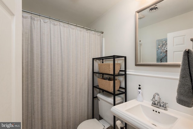 bathroom featuring a shower with shower curtain, toilet, and sink