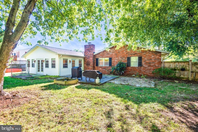 rear view of property featuring a wooden deck, a yard, and a patio