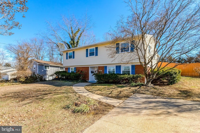 colonial home with a front yard, brick siding, and fence