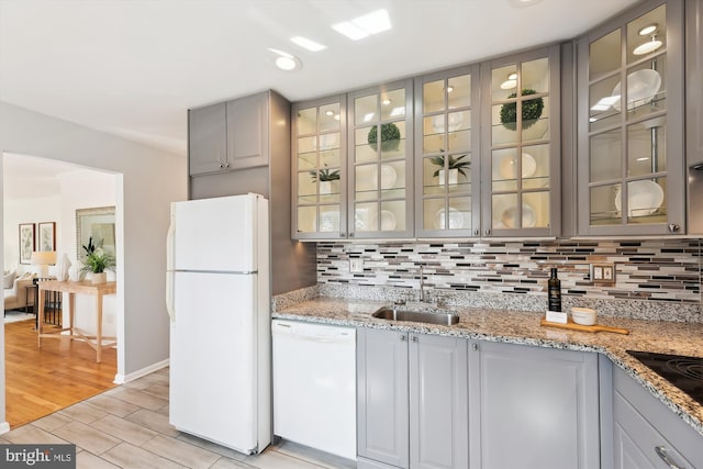 kitchen featuring decorative backsplash, white appliances, a sink, and gray cabinetry