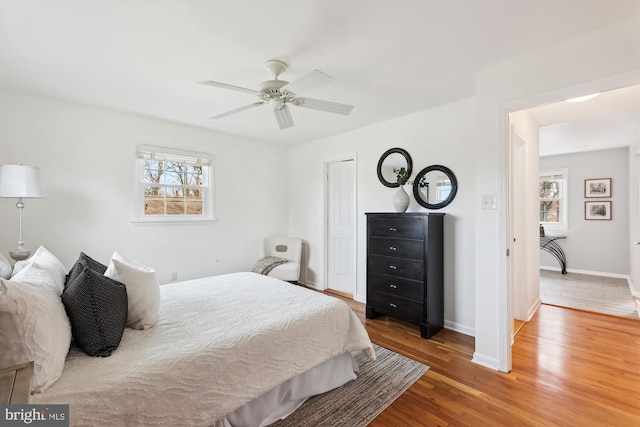 bedroom featuring ceiling fan, a closet, baseboards, and wood finished floors