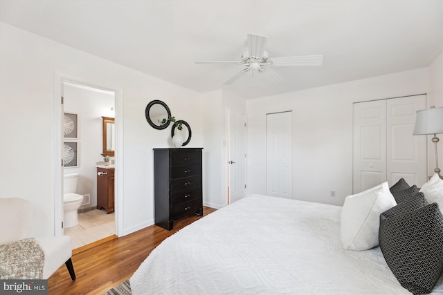 bedroom with two closets, a ceiling fan, connected bathroom, wood finished floors, and baseboards