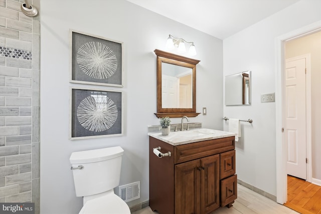 bathroom with baseboards, visible vents, toilet, wood finished floors, and vanity