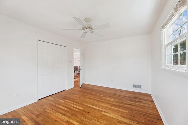 unfurnished bedroom with baseboards, a closet, visible vents, and light wood-style floors