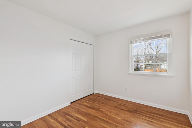 unfurnished bedroom featuring a closet, wood finished floors, and baseboards