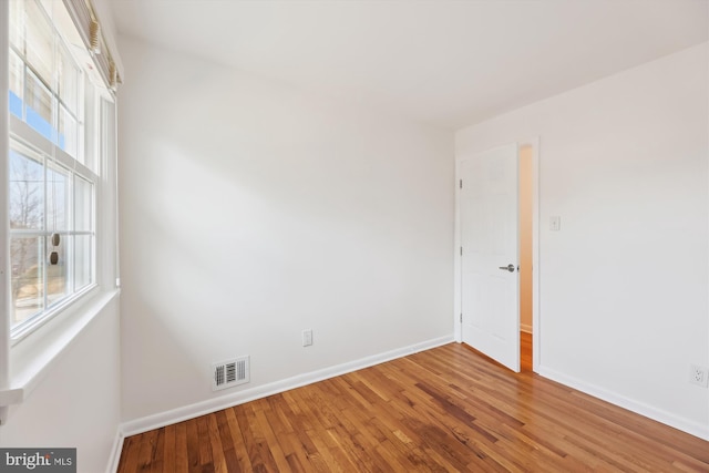 spare room featuring visible vents, baseboards, and wood finished floors