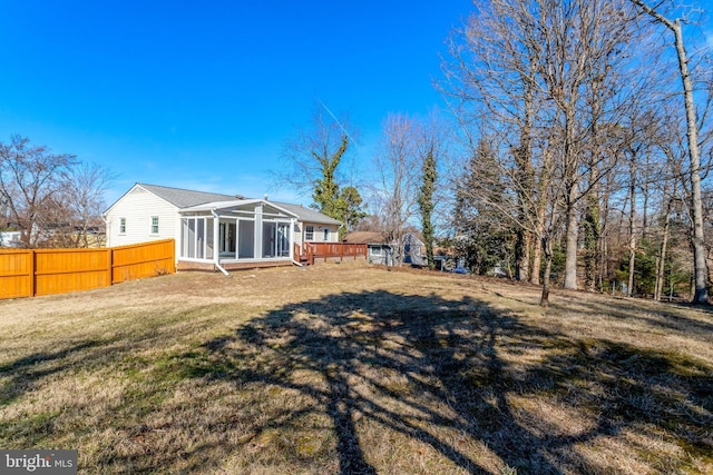 back of house featuring a lawn, fence, and a sunroom