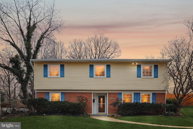 colonial home featuring a yard, brick siding, and fence