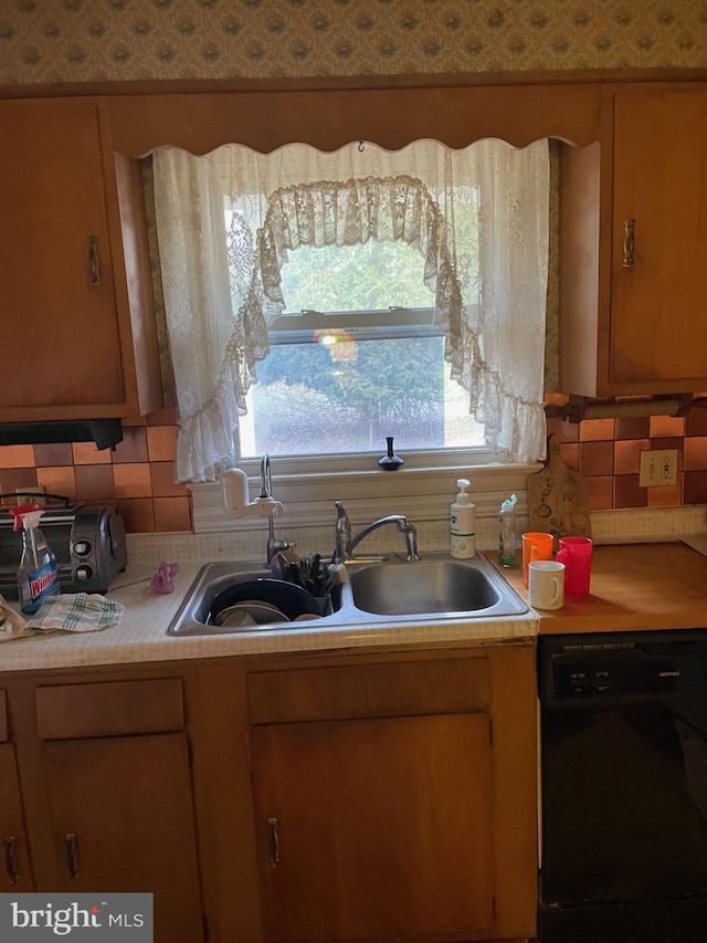 kitchen featuring decorative backsplash, dishwasher, and sink