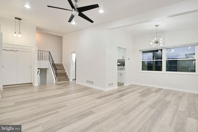 unfurnished living room featuring ceiling fan with notable chandelier and light hardwood / wood-style flooring