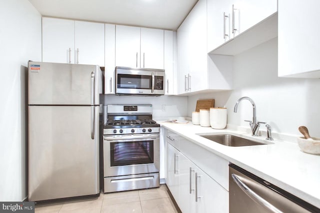 kitchen with light tile patterned floors, stainless steel appliances, white cabinetry, and sink