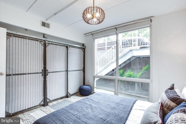 bedroom with hardwood / wood-style flooring and an inviting chandelier