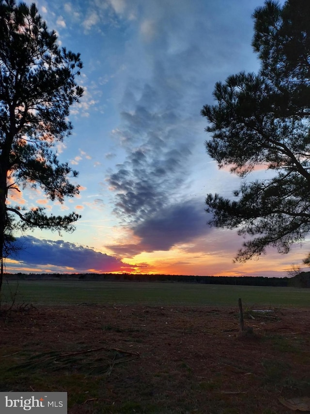 yard at dusk featuring a rural view