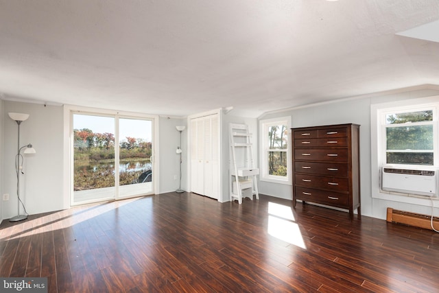 unfurnished living room with plenty of natural light, cooling unit, dark hardwood / wood-style floors, and a baseboard heating unit