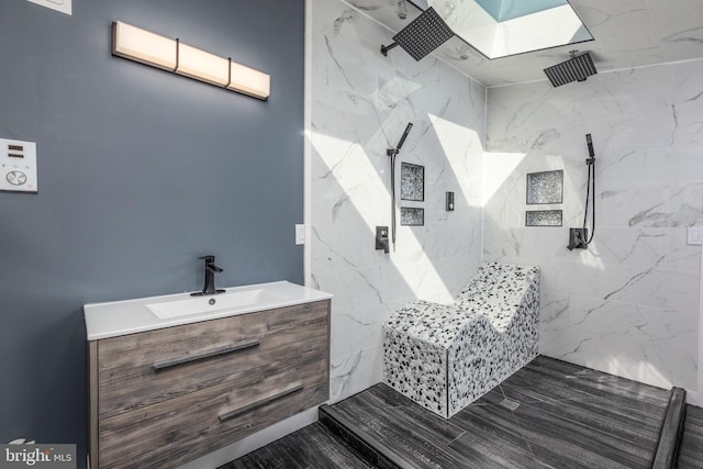 bathroom with a tile shower, vanity, and hardwood / wood-style flooring