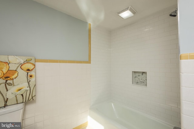 bathroom with toilet and tiled shower / bath