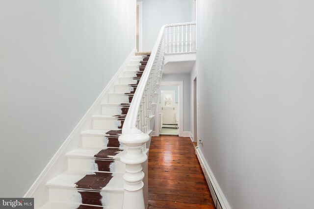 stairway featuring baseboard heating and hardwood / wood-style flooring