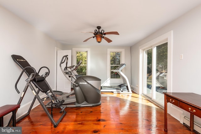 workout area with ceiling fan, dark wood-type flooring, and a healthy amount of sunlight