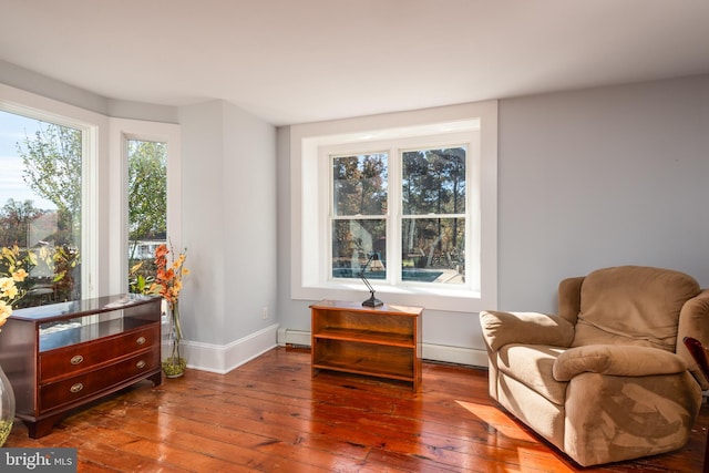 living area featuring wood-type flooring and a baseboard heating unit