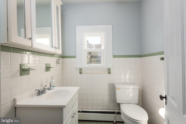 bathroom featuring vanity, toilet, baseboard heating, and tile walls